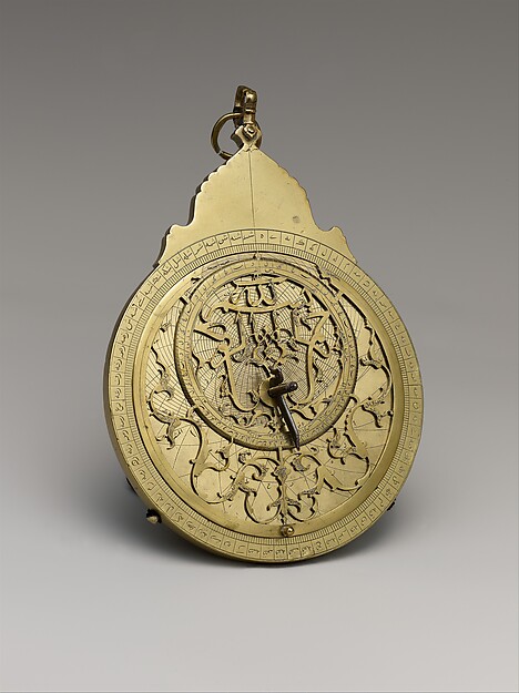 An engraved brass astrolabe with circular scales and a pierced star map.